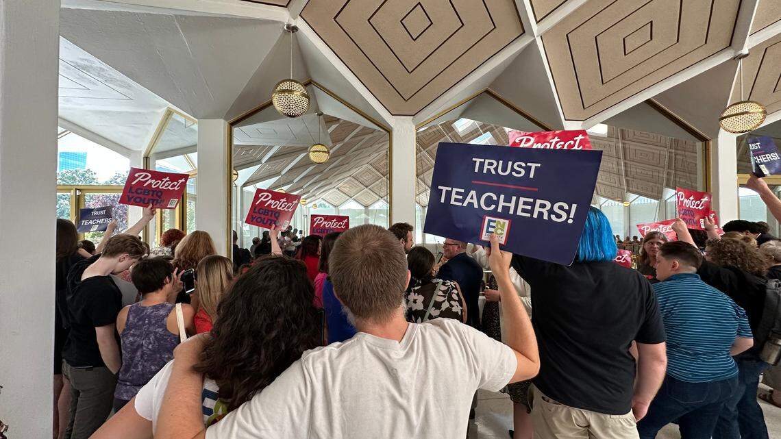 Opponents of a slew of bills targeting the LGBTQ+ community hold up signs outside the House gallery in protest at the Legislative Building in downtown Raleigh on Wednesday, Aug. 16, 2023.