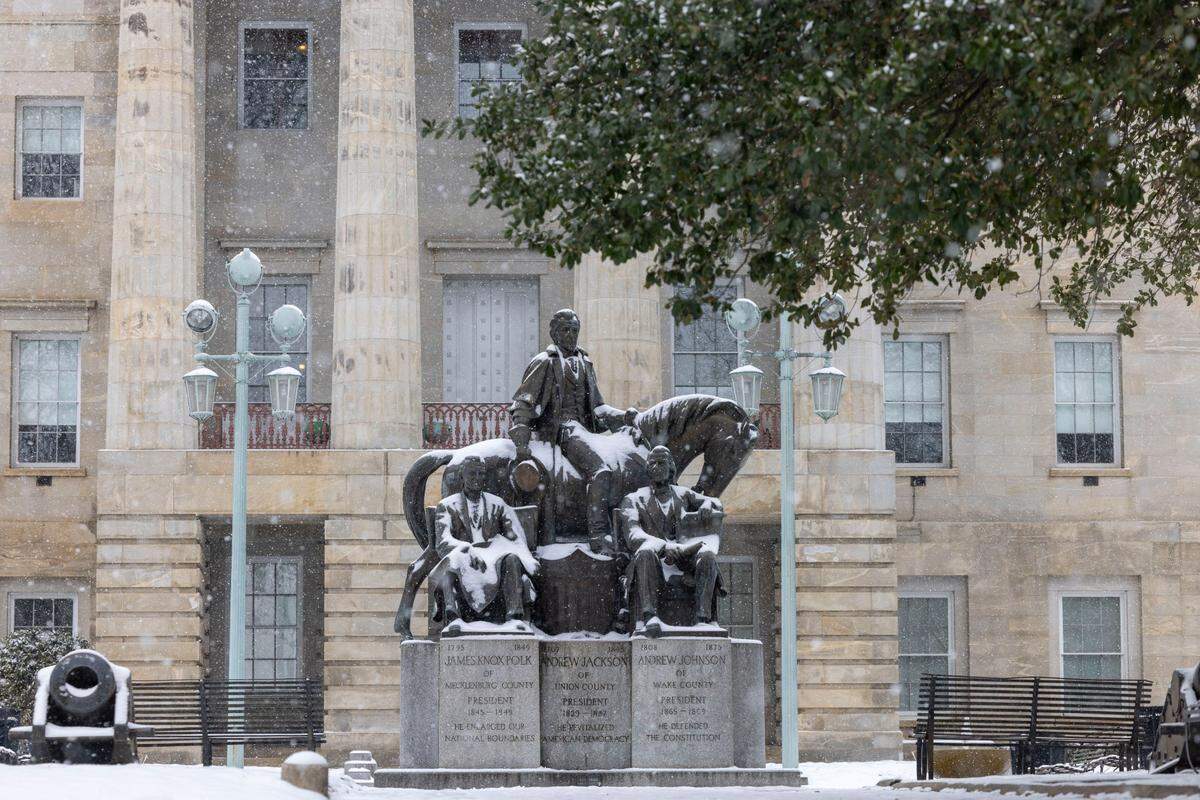 A light snow falls over the State Capitol grounds, dusting the North Carolina Presidents monument on Thursday afternoon February 20, 2025 in Raleigh, N.C.