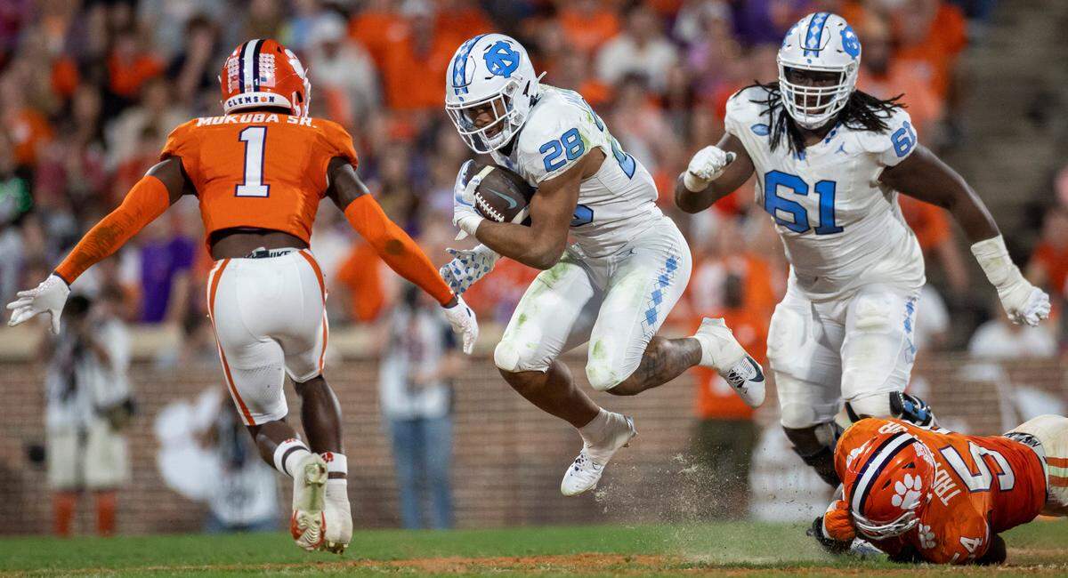 North Carolina’s Omarion Hampton (28) looks for running against Clemson’s Andrew Mukuba (1) on a three-yard gain in the third quarter on Saturday, November 18, 2023 at Memorial Stadium in Clemson, S.C.