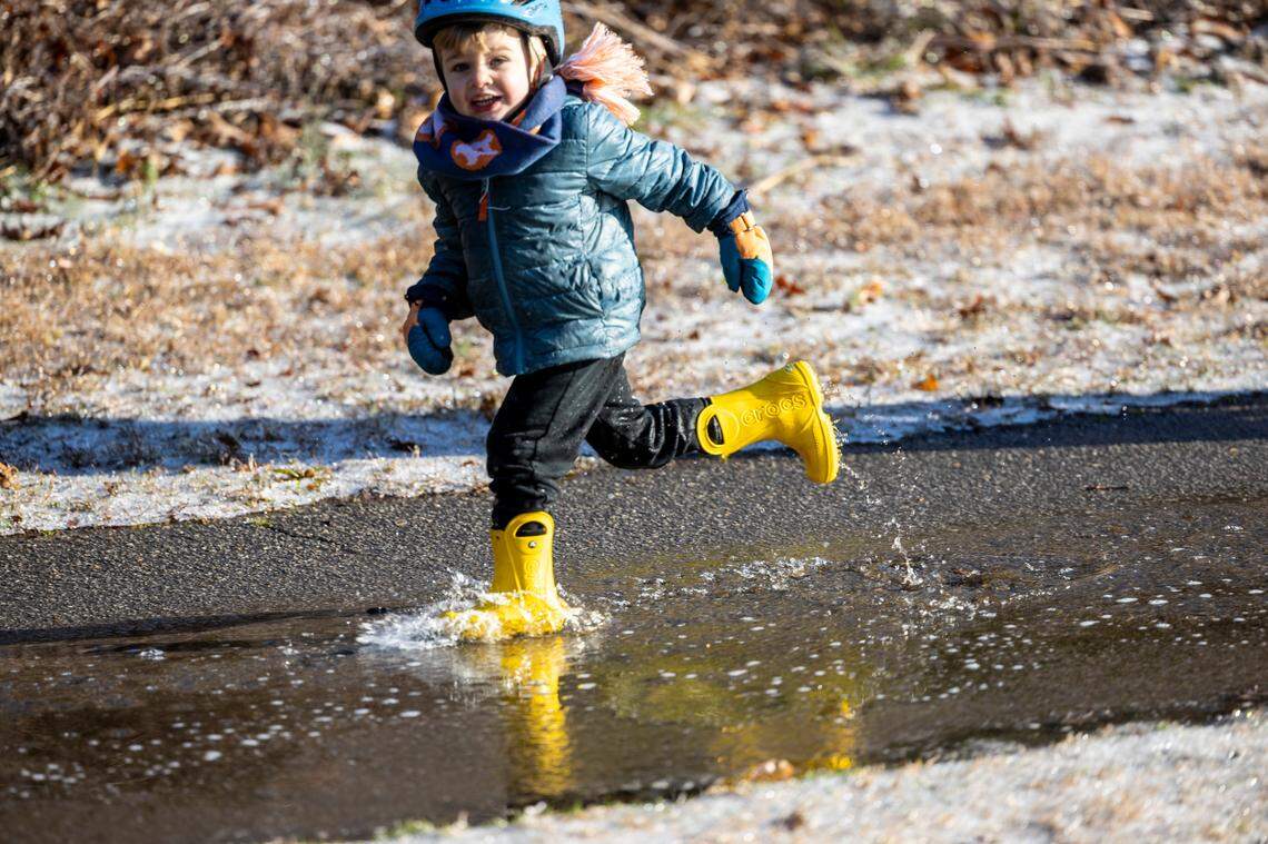 Galo Gainey, 3, splashes through a puddle as morning sunlight begins to melt the snow and ice at Dorothea Dix Park in Raleigh on Saturday, Dec. 11, 2025.