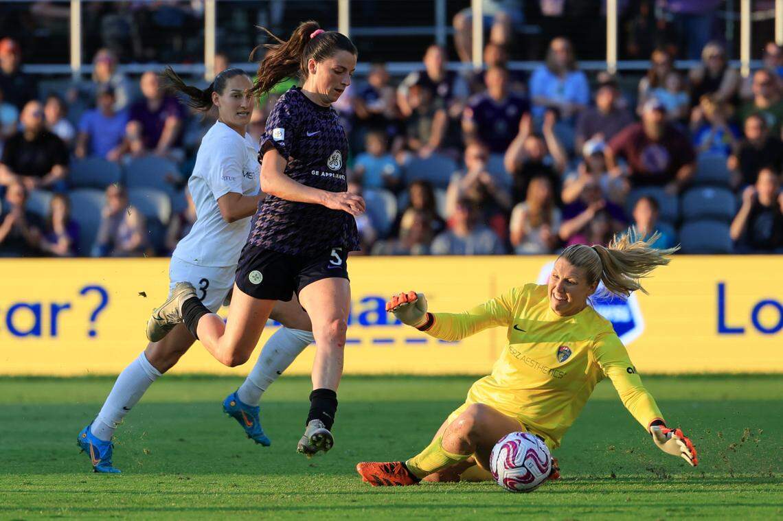 Racing Louisville FC defender Paige Monaghan (5) takes a shot at goal as North Carolina Courage goalkeeper Casey Murphy (1) attempts to block it during the first half at Lynn Family Stadium.