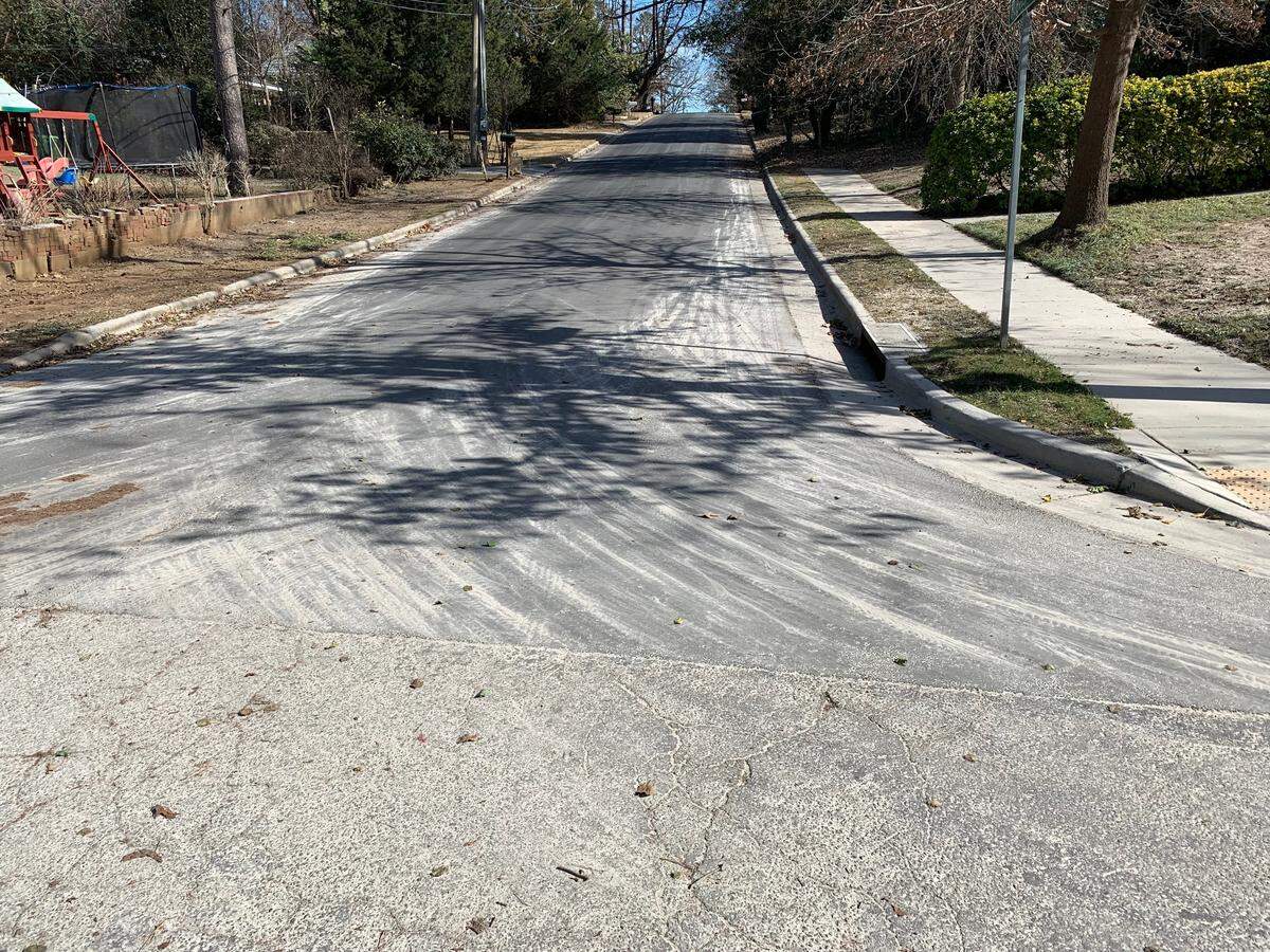 White dust from a nearby concrete grinding operation covers the pavement where Reavis and Lorimer roads meet near the Western Boulevard interchange of the Beltline.