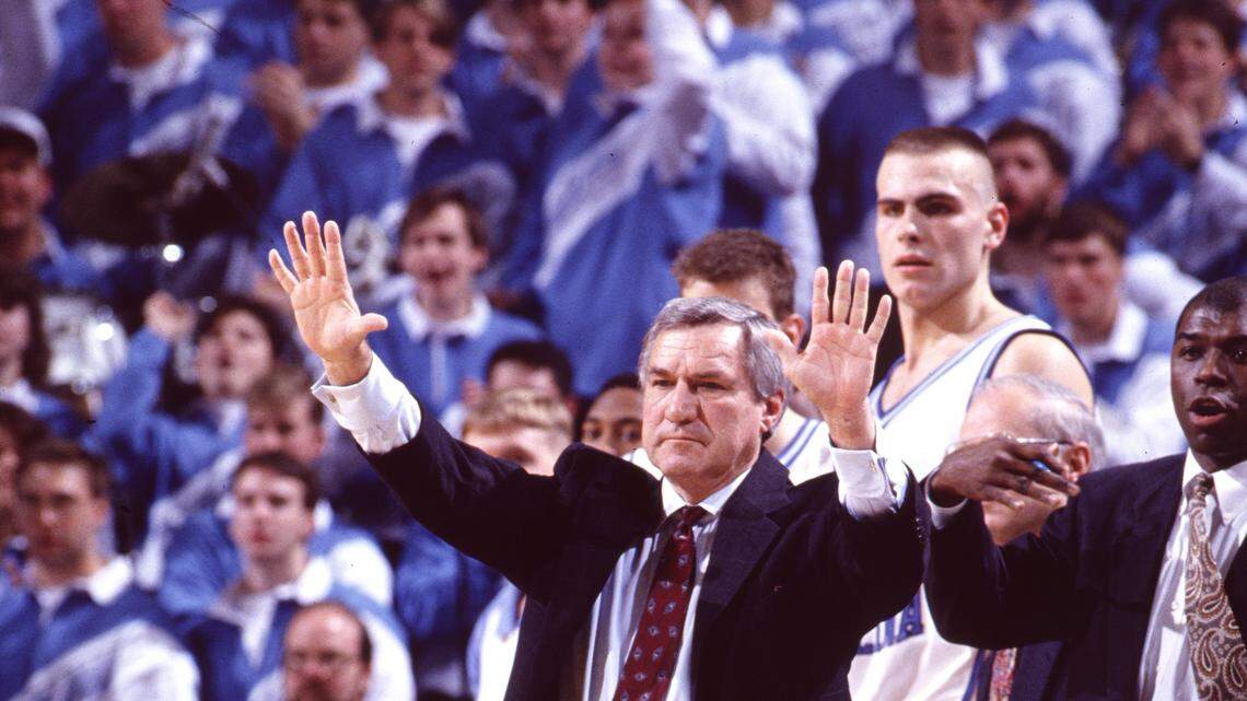 A file photo of UNC coach Dean Smith working the sidelines of a game in the Smith Center in Chapel Hill, NC. Center Eric Montross is in the background, and former player and assitant Phil Ford at right.