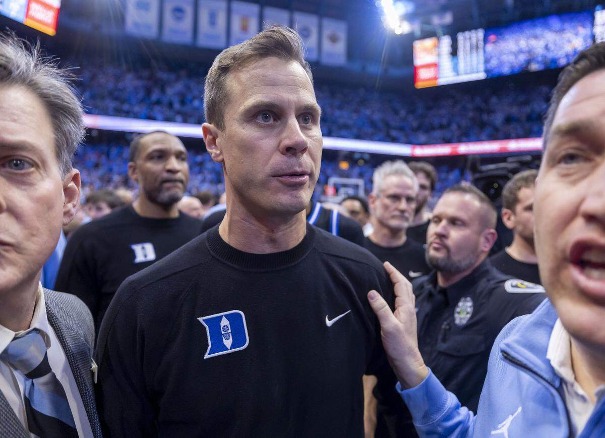 Duke coach Jon Scheyer and his players try to get off the Smith Center Court following a three-point shot by North Carolina guard Seth Trimble on Saturday, February 7, 2026 at the Smith Center in Chapel Hill, N.C.  Scheyer voiced his disappointment at not being able to get off the court safely at the end of the game once fans stormed the court. 