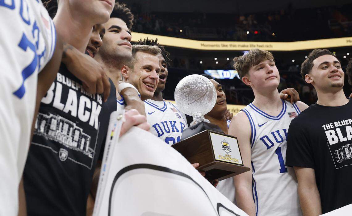 Duke head coach Jon Scheyer holds the championship trophy while posing with the team after Duke’s 68-63 victory over Michigan in the Capital Showcase at Capital One Arena in Washington, D.C., Saturday, Feb. 21, 2026.