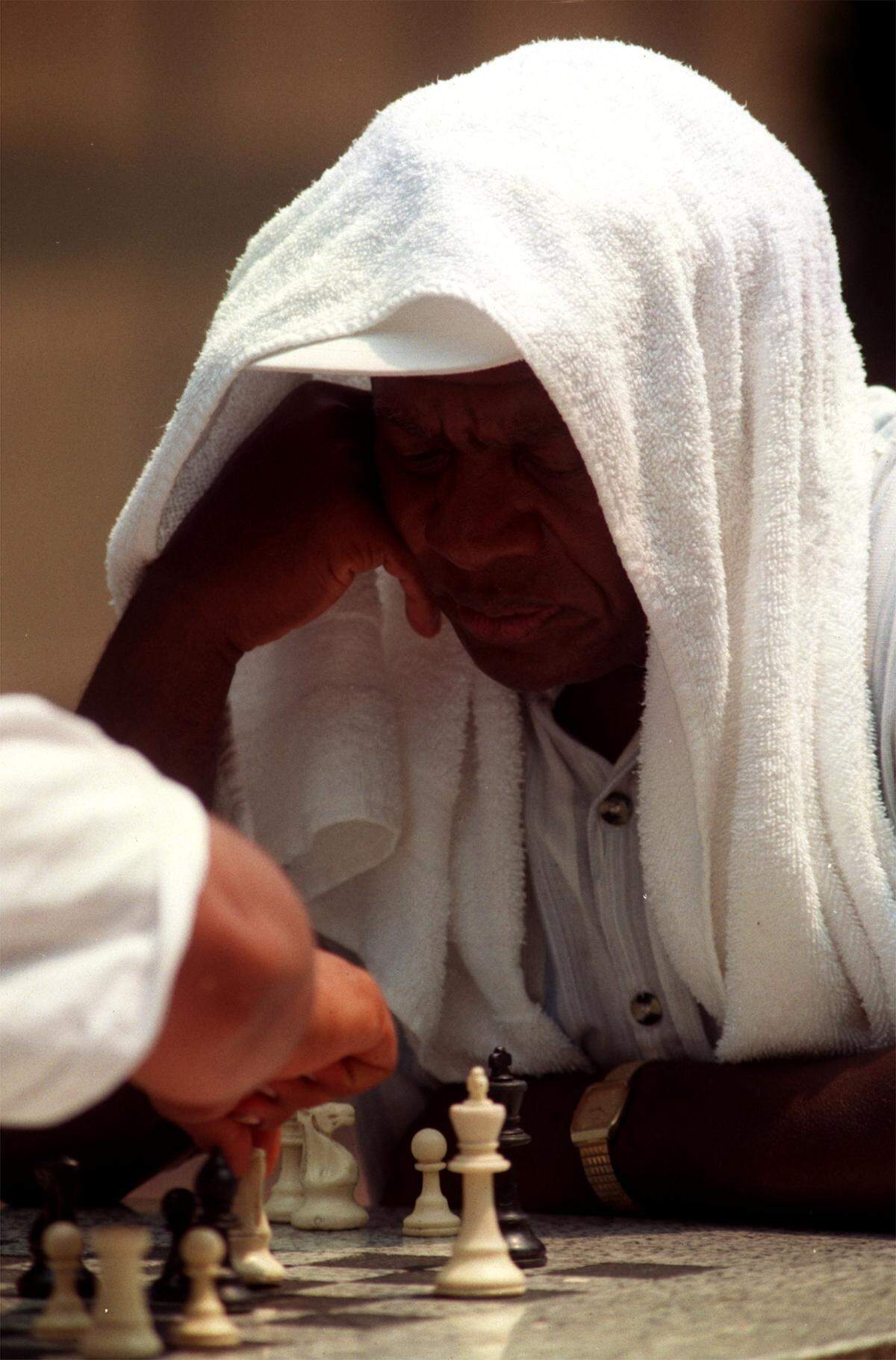 HOT.MW.070699.JAC- Raleigh, NC- 7/6/99- Draped in a cool towel, Sherman Leathers of Raleigh ignores the heat as he plays chess with Jesus Rosales in the Fayetteville pedestrian mall on July 6, 1999. 
