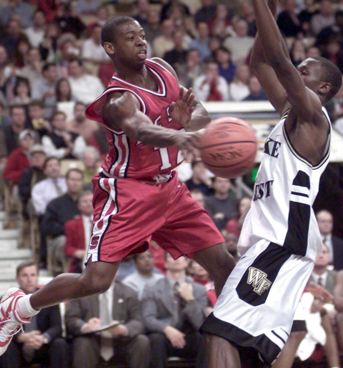 N.C. State's Justin Gainey (12) dishes the ball off and draws the foul from Wake Forest's Broderick Hicks (3) during their game in 2000.