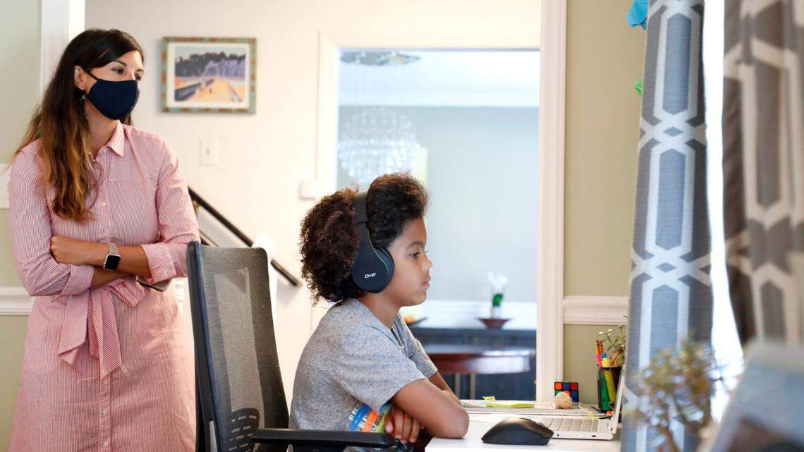 As his mother Juliette takes a peak, Harper Grimmett attends his day of classes as a sixth grader at Ligon Middle School while at their home in Raleigh, N.C. Monday, August 17, 2020. He’s among the students in Wake County’s Virtual Academy program.