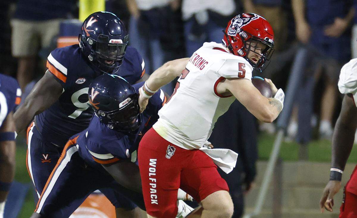 N.C. State quarterback Brennan Armstrong (5) escapes the Virginia defense on a scramble during the first half of N.C. State’s game against Virginia at Scott Stadium in Charlottesville, Va., Friday, Sept. 22, 2023.