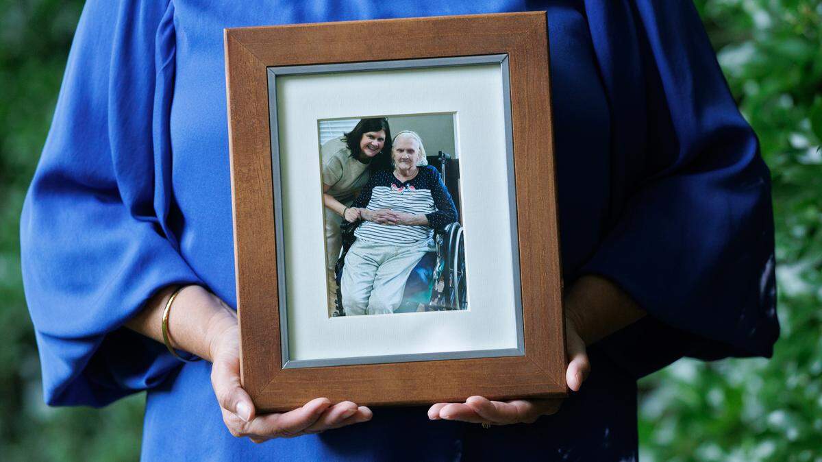Sarah Cope, photographed on Tuesday, June 17, 2025, at her home in Garner, N.C., holds a photograph of herself and her mother, Linda Davis. Davis, who was diagnosed with dementia, lives in a nursing home in Harnett County. Cope says without Medicaid, she’s unsure how her family would care for her mother.