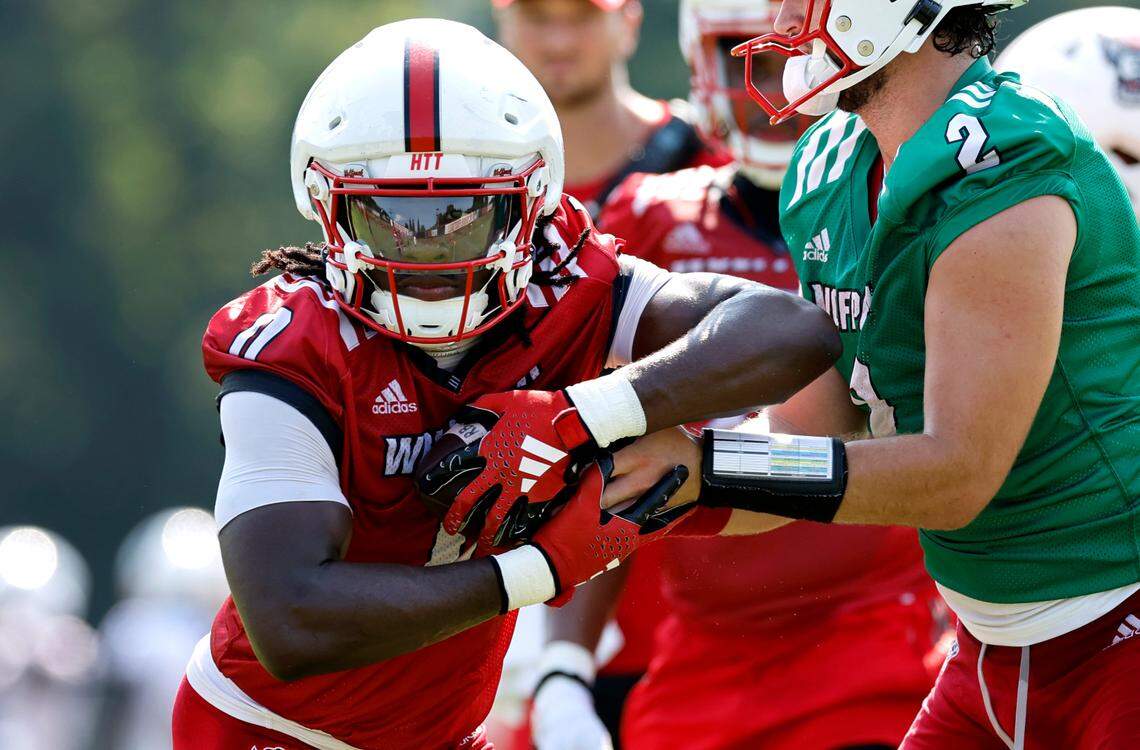 N.C. State running back Kendrick Raphael (0) takes the handoff from quarterback Grayson McCall (2) during the Wolfpack’s first practice in Raleigh, N.C., Wednesday, July 31, 2024.