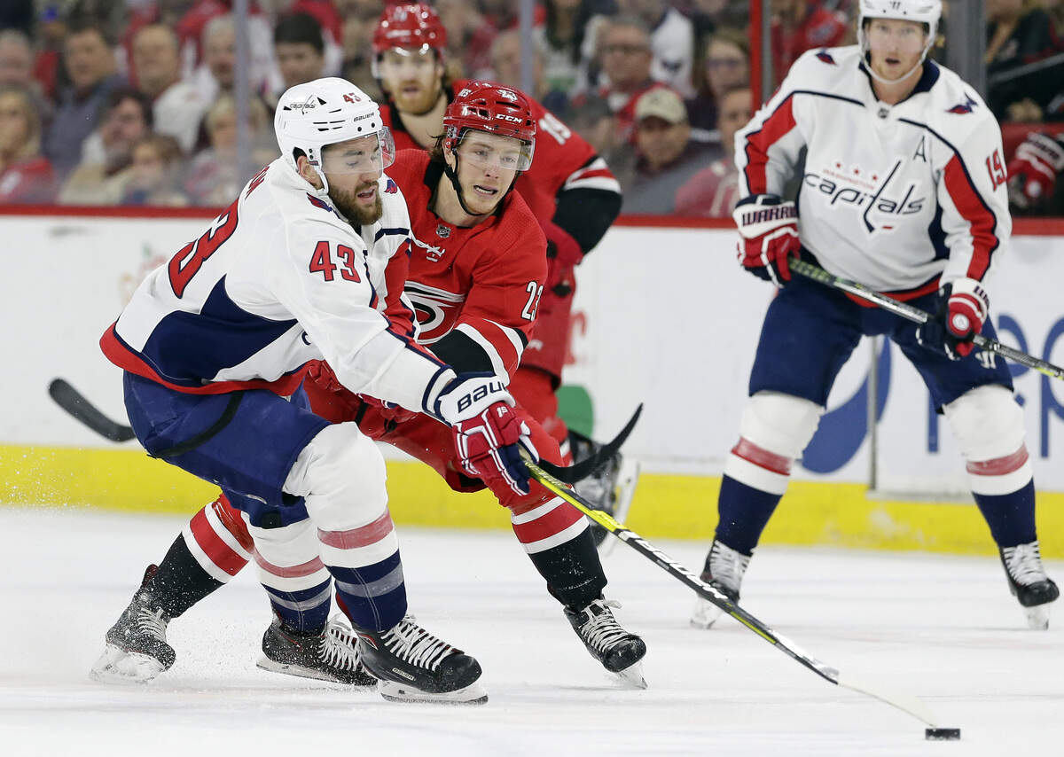 Washington Capitals’ Tom Wilson (43) and Carolina Hurricanes’ Brock McGinn, right, chase the puck during the first period of an NHL hockey game in Raleigh, N.C., Thursday, March 28, 2019. (AP Photo/Gerry Broome)