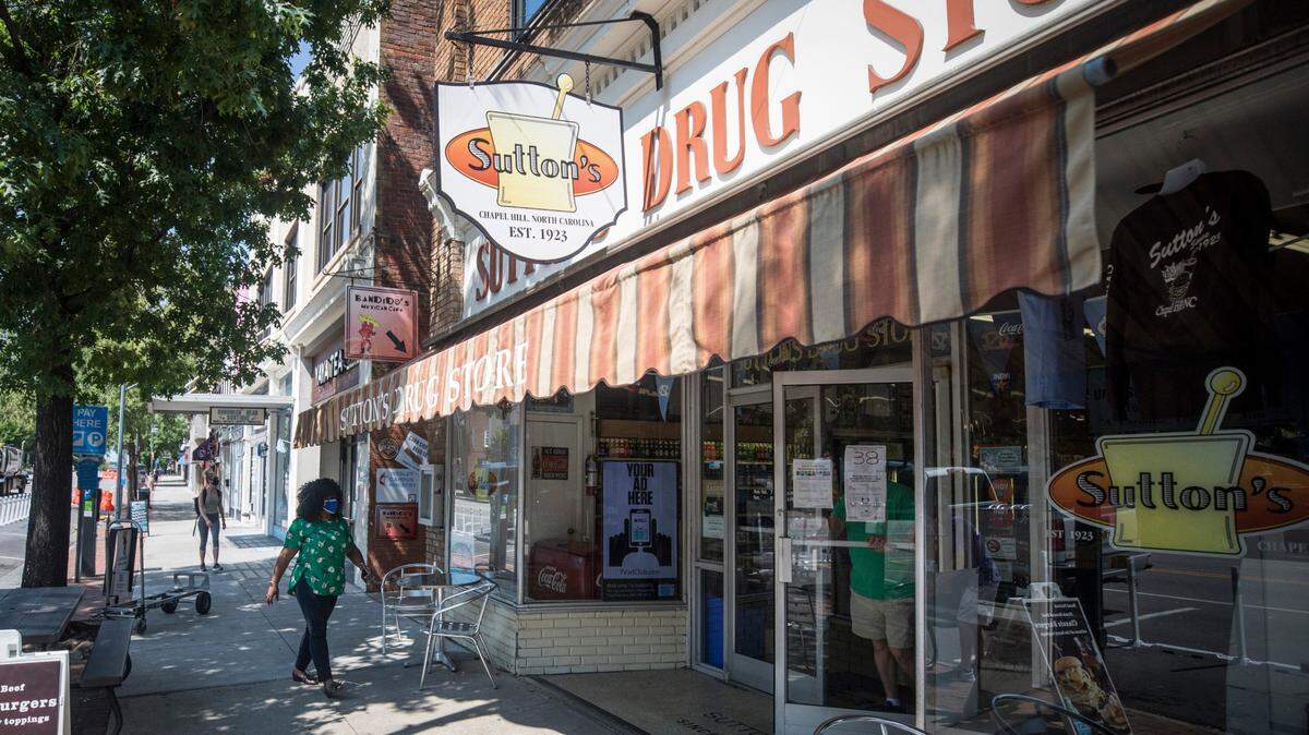 A patron of Sutton’s Drug Store walks towards the Franklin St. establishment in Chapel Hill, N.C. during what would normally be a bustling lunch hour on Thursday, Aug. 27, 2020.