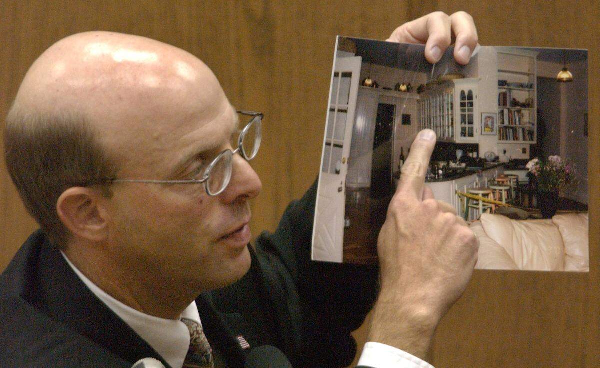 SBI Special Agent and blood spatter expert Duane Deaver holds up a photo of Michael Peterson’s kitchen area to the jury as his second day of testimony continued in Peterson’s murder trial.