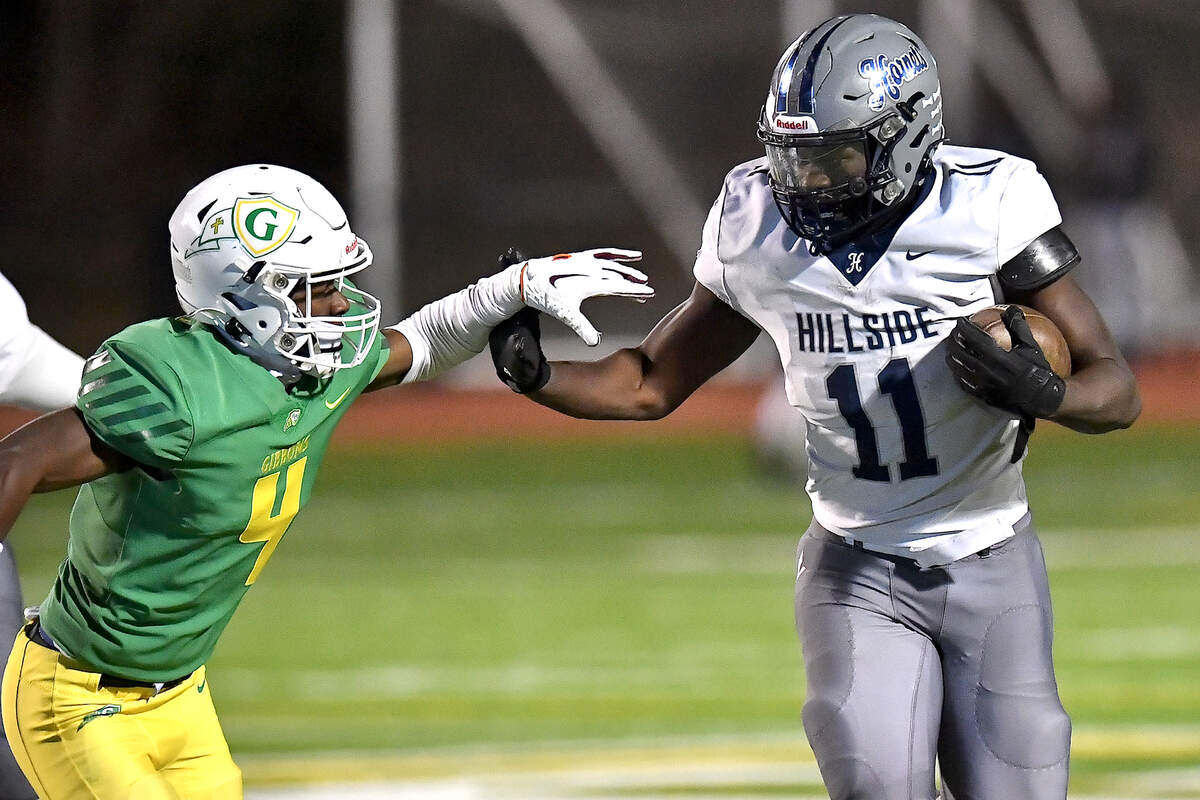 Hillside running back Ameil Braswell (11) fends off Cardinal Gibbons’ Braylon Peebles (4) during the second half. The Cardinal Gibbons Crusaders and the Durham Hillside Hornets met in the third round of the NCHSAA 4A playoffs in Raleigh, N.C. on November 29, 2024.