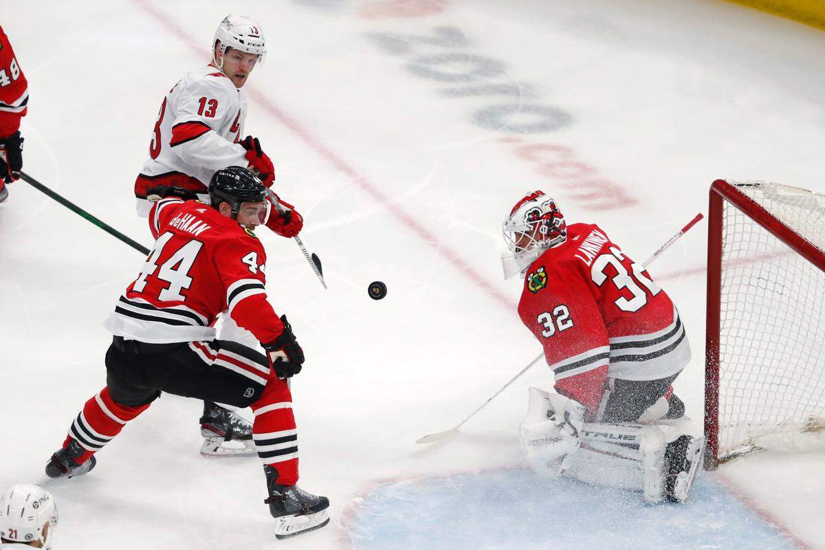 Carolina Hurricanes left wing Warren Foegele (13) reaches for the puck in front of Chicago Blackhawks defenseman Calvin de Haan (44) and goaltender Kevin Lankinen (32) during the first period of an NHL hockey game Thursday, April 1, 2021, in Chicago. (AP Photo/Jeff Haynes)