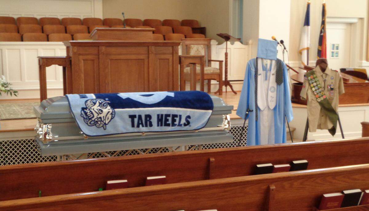 Joe Brown’s casket at his funeral in 2018, draped with a Carolina blanket, and his graduation gown just inches to the right.