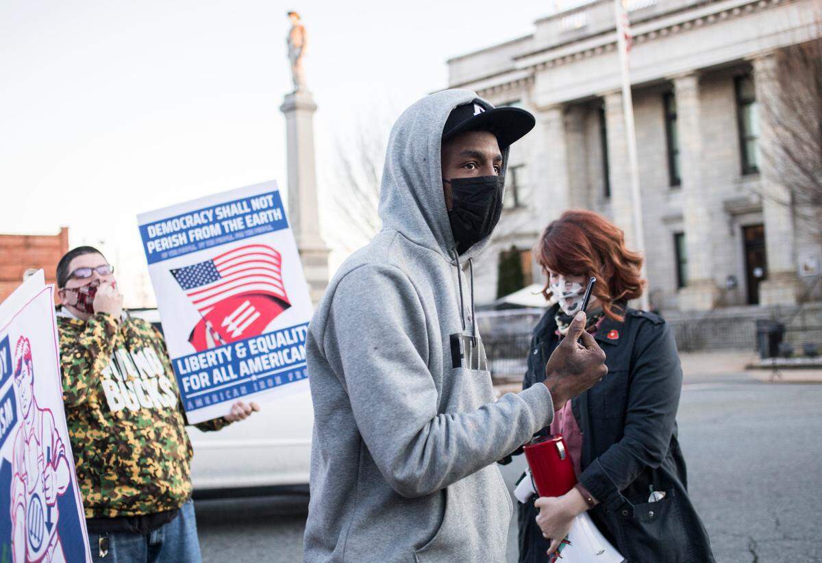 Avery Harvey talks to fellow Occupy Graham demonstrators on Jan. 13, 2021 before their group marches to Rep. Ted Budd’s office in Graham, N.C. to demand that he condemn the insurrection at the U.S. Capitol.