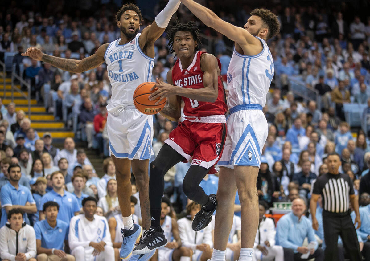 N.C. State’s Terquavion Smith (0) drives to the basket between North Carolina’s Leaky Black (1) and Pete Nance (32) during the first half on Saturday, January 21, 2023 at the Smith Center in Chapel Hill, N.C.