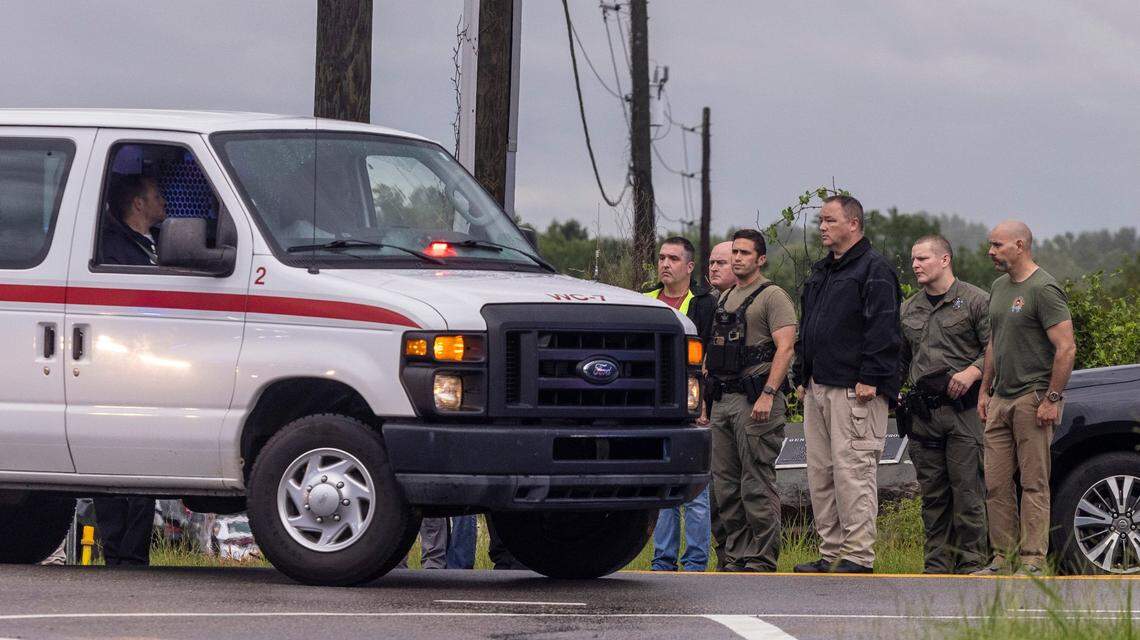 Law enforcement officers, watch as a procession leaves the scene where a deputy was shot and killed in eastern Wake County near the intersection of Auburn Knightdale and Battle Bridge Roads Friday, Aug. 12, 2022.