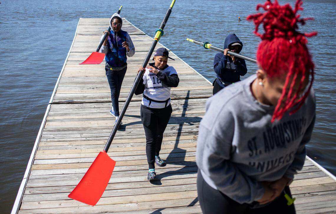 Members of the first women’s crew team at Saint Augustine’s University carry oars from a dock at Lake Wheeler in Raleigh, N.C. after rowing practice on Sunday, April 10, 2022.