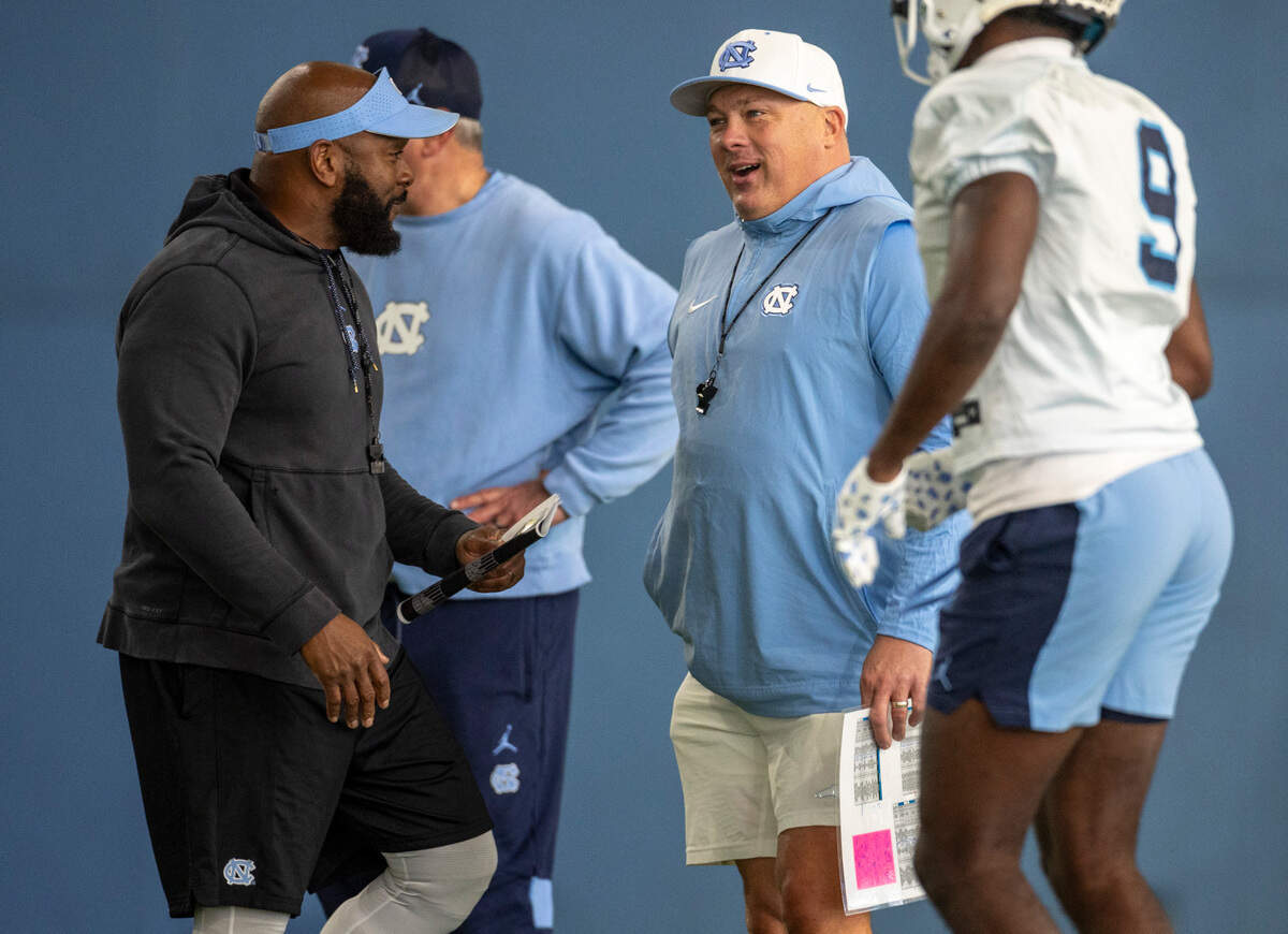 North Carolina defensive coordinator Geoff Collins, center, talks with Charlton Warren assistant head coach for defense, during the opening day of spring football practice on Tuesday, March 19, 2024 in Chapel Hill, N.C.