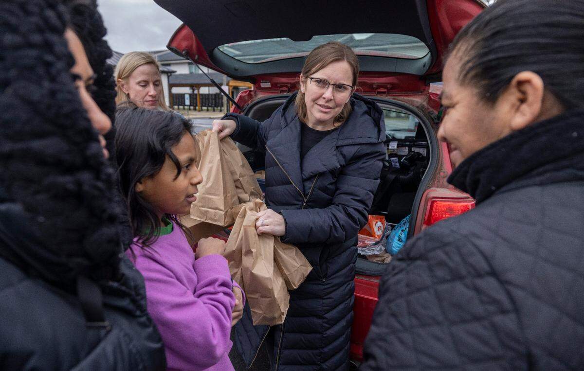 Caitlin Georgas hands out bag lunches to families with children displaced by closed Durham schools at an apartment complex on Garrett Road on Wednesday, January 31, 2024 in Durham, N.C. Georges and other volunteers from Jubilee Baptist Church were responsible for providing the food and preparing the meals.