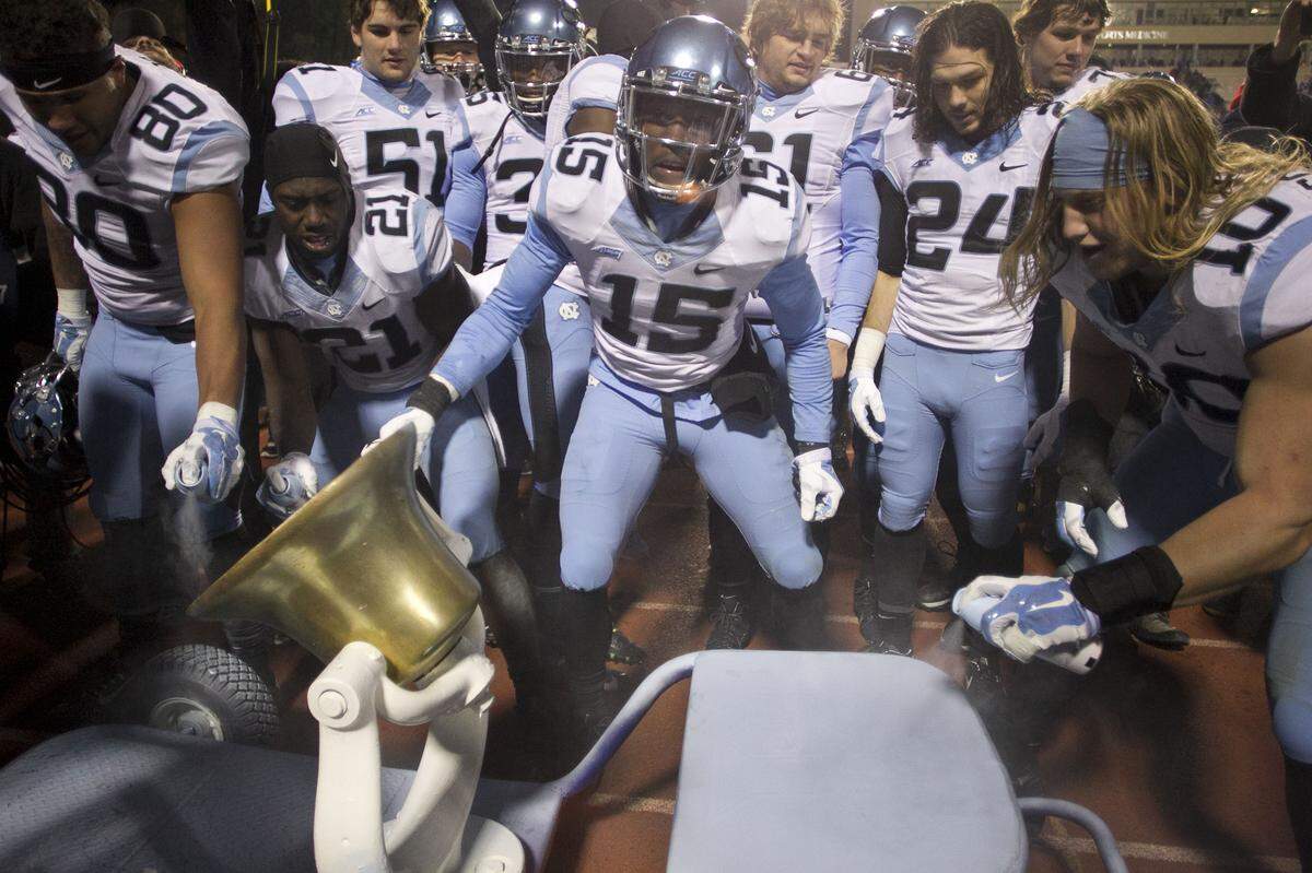 UNC's Donnie Miles (15) and his teammates celebrate their 45-20 victory over Duke by painting the victory bell Carolina blue on Thursday, November 19, 2014 at Wallace Wade Stadium in Durham, N.C.