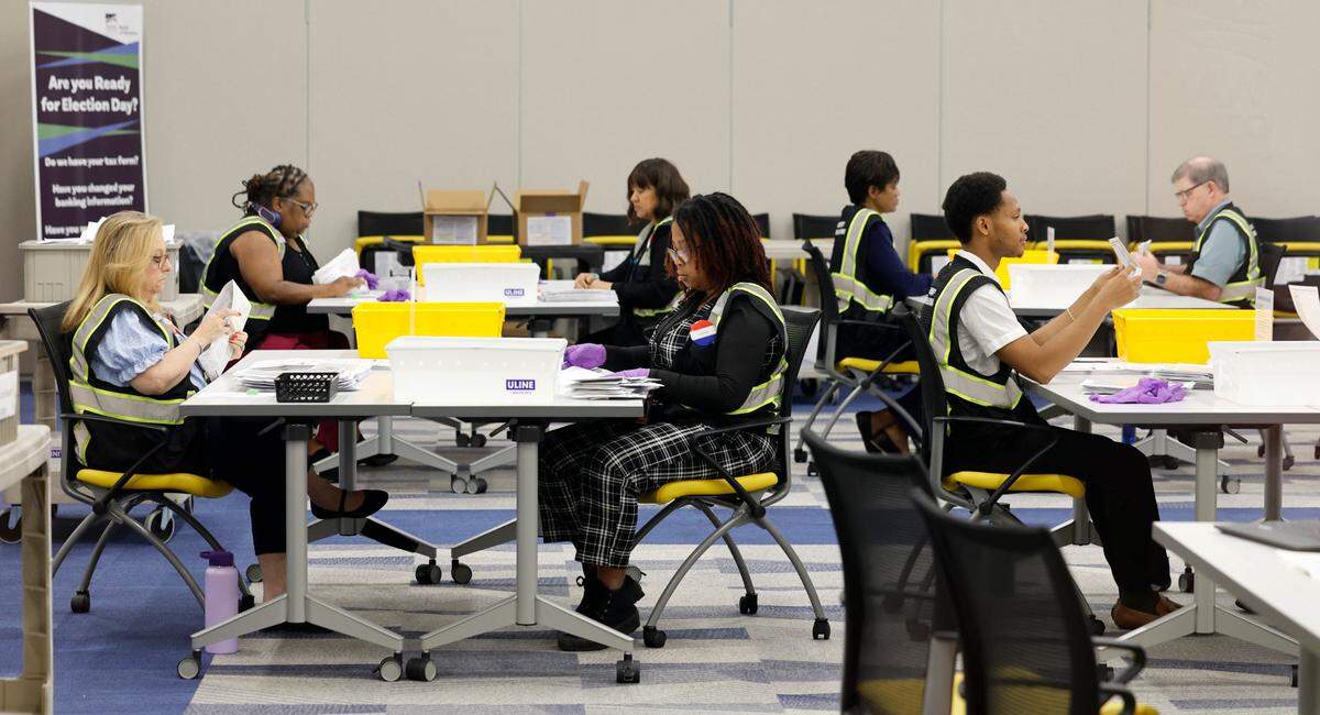 Board of Elections workers open, straighten and flatten approved absentee ballots at the Wake County Board of Elections Operations Center in Raleigh, N.C., Tuesday, Oct. 8, 2024.