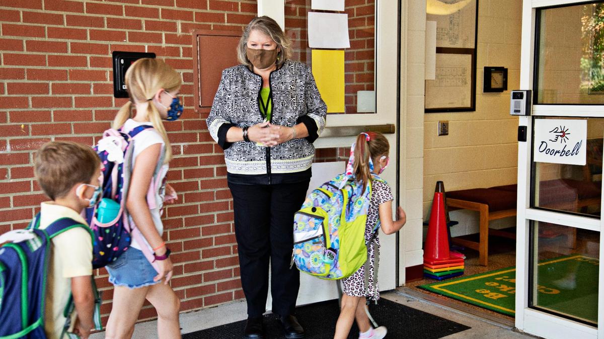 Principal Fay Jones, center, greets students as they enter Carpenter Elementary School in Cary on Thursday morning, Aug. 19, 2021. A change in how North Carolina calculates pay could cost principals thousands of dollars. .