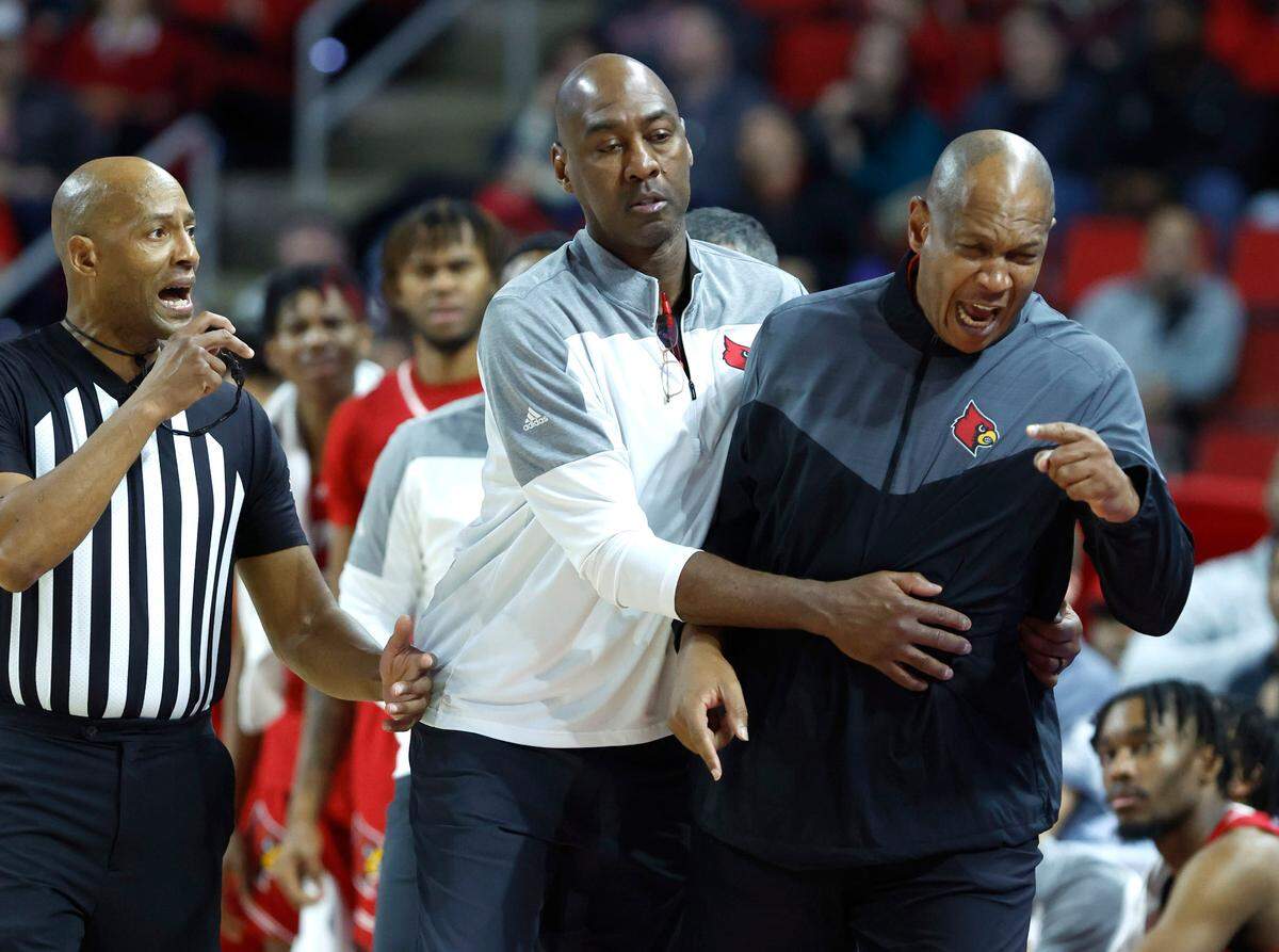 Louisville associate head coach Danny Manning holds back head coach Kenny Payne as he argues with official Bert Smith during the second half of N.C. State’s 76-64 victory over Louisville at PNC Arena in Raleigh, N.C., Thursday, Dec. 22, 2022. Payne was given a technical.