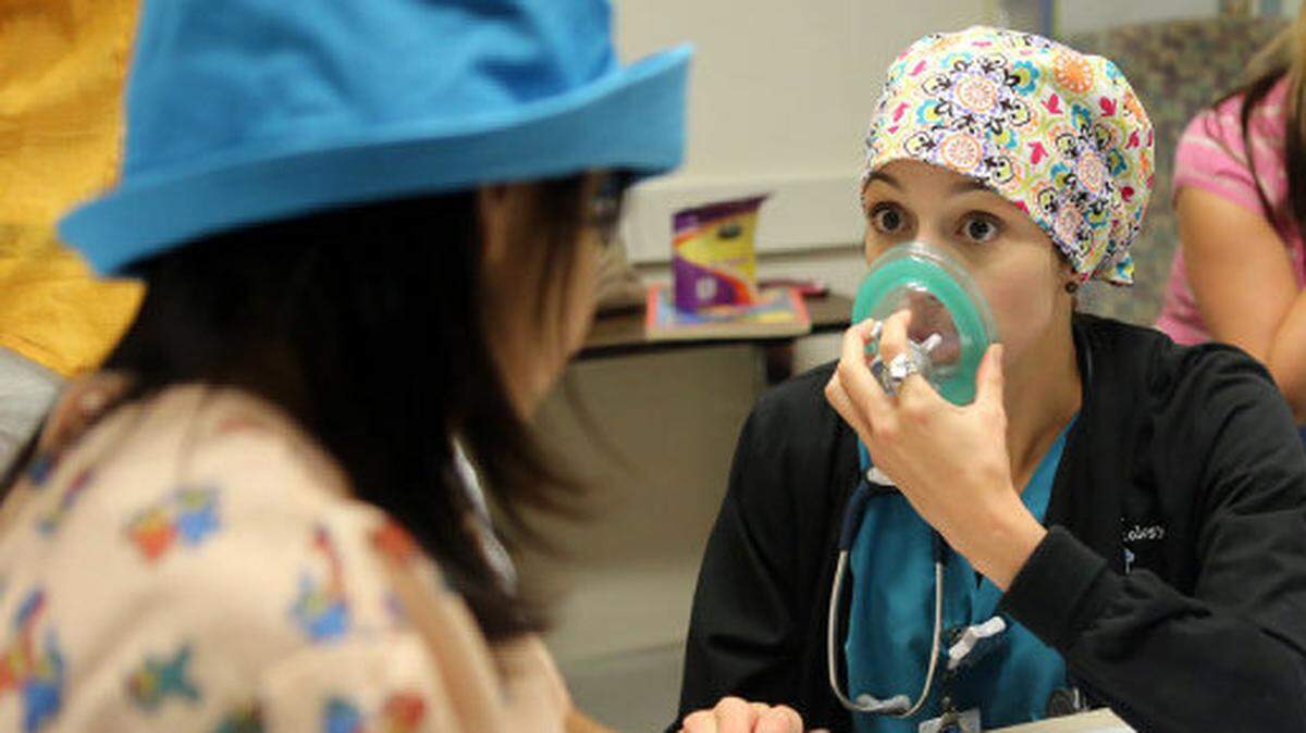 Certified registered nurse anesthetist Dori Smith shows a young patient how her face mask works before a procedure.