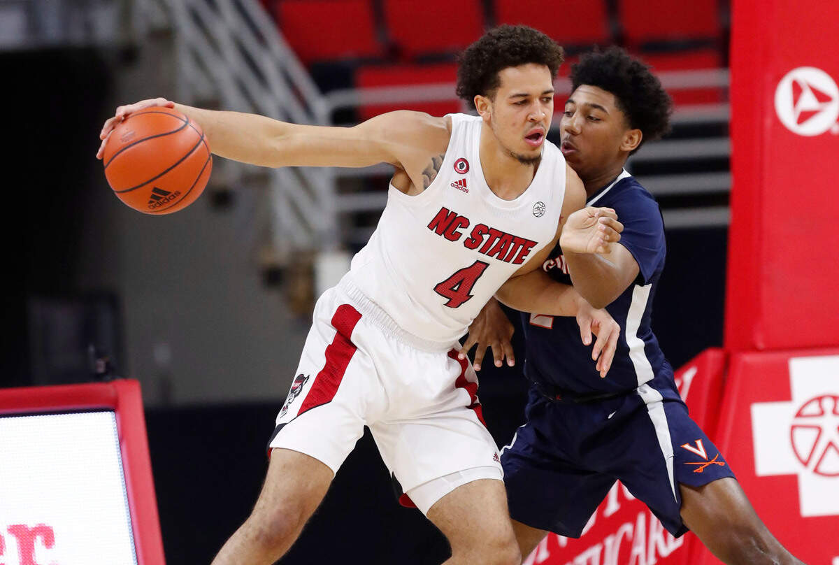 N.C. State’s Jericole Hellems (4) looks for room as Virginia’s Reece Beekman (2) defends during the first half of N.C. State’s game against Virginia at PNC Arena in Raleigh, N.C., Wednesday, February 3, 2021.