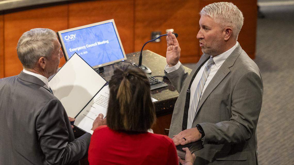 Cary Mayor Harold Weinbrecht, left, swears in Russ Overton, deputy town manager, during an emergency meeting in December at Cary Town Hall. 