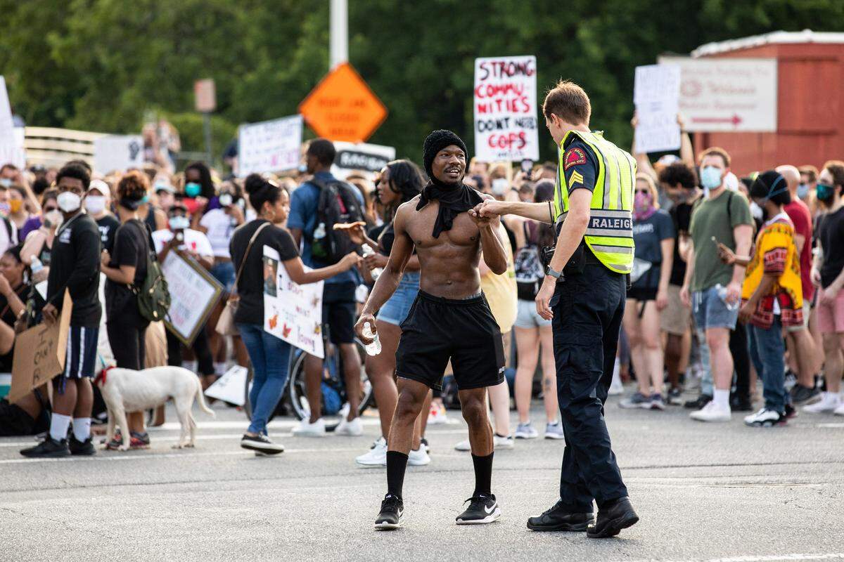 A protester bumps fist with a Raleigh Police Officer during a demonstration against the police killing of George Floyd on Hillsborough Street in Raleigh, N.C. on Thursday, Jun. 4, 2020.