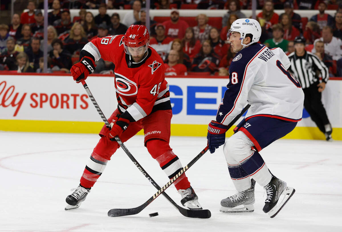 Carolina left wing Jordan Martinook (48) keeps the puck from Columbus defenseman Zach Werenski (8) during the second period of the Carolina Hurricanes game against the Columbus Blue Jackets at PNC Arena in Raleigh, N.C., Wednesday, Oct. 12, 2022.