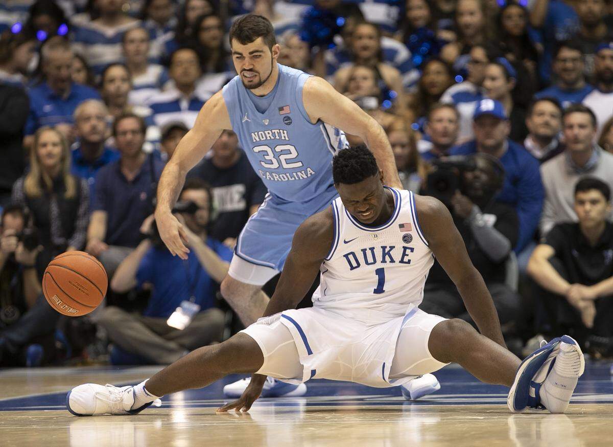 Duke’s Zion Williamson (1) falls to the court under North Carolina’s Luke Maye (32), injuring his right knee on Feb. 20. The two teams meet again March 9 in Chapel Hill and might play one more time the next week at the ACC tournament in Charlotte.