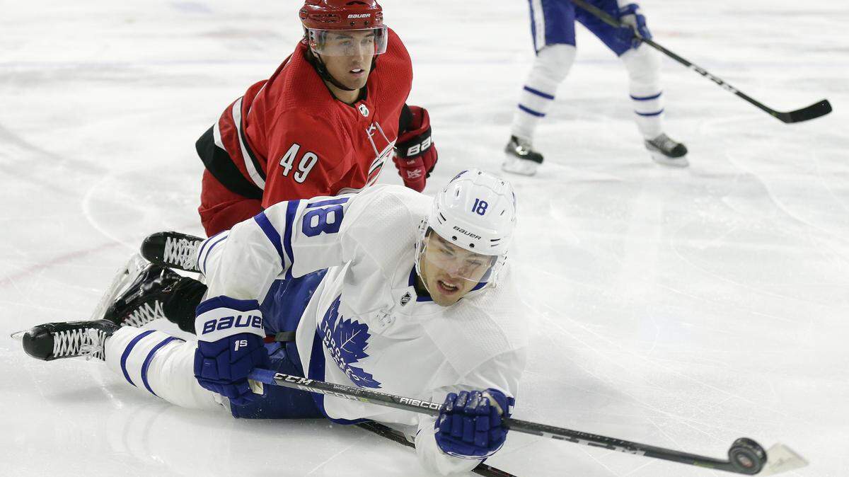 Toronto Maple Leafs’ Andreas Johnsson (18), of Sweden, falls to the ice while chasing the puck with Carolina Hurricanes’ Victor Rask (49), of Sweden, during the first period of an NHLgame on Nov. 21, 2018.