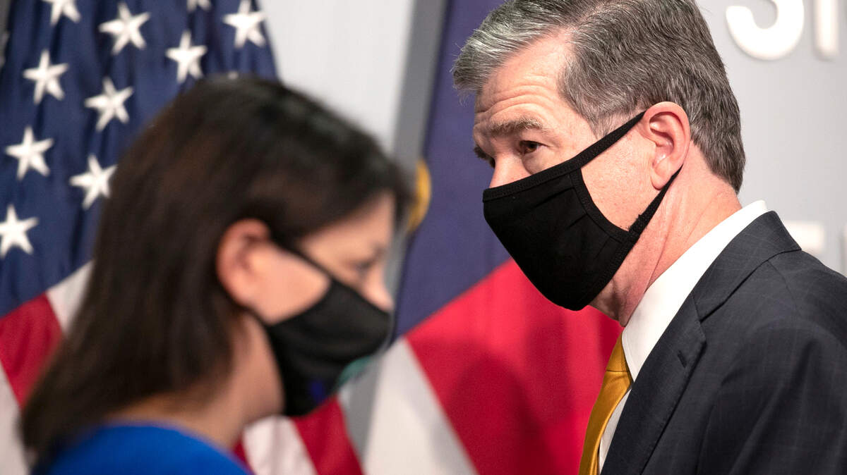 North Carolina Governor Roy Cooper and Dr. Mandy Cohen, Secretary of the North Carolina Department of Health and Human Services exchanges places at the podium during a press briefing on the COVID-19 virus on Tuesday, November 10, 2020 at the Emergency Operations Center in Raleigh, N.C.