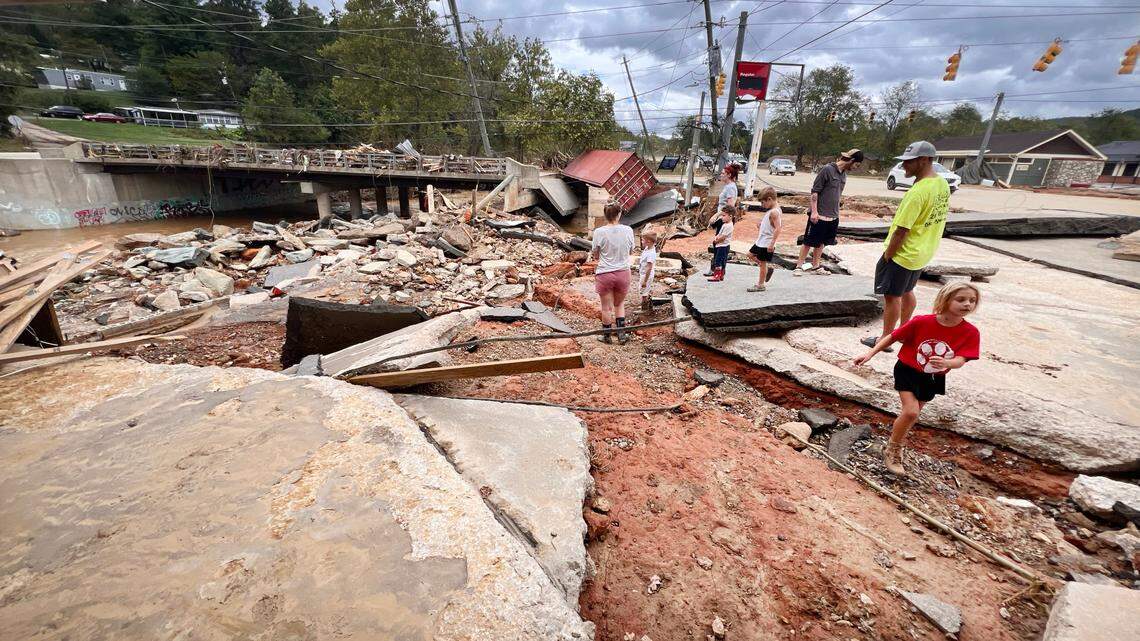 People examine some of the extensive damage caused by flooding from Helene along the Swannanoa River in Swannanoa, N.C., Sunday, Sept. 29, 2024.