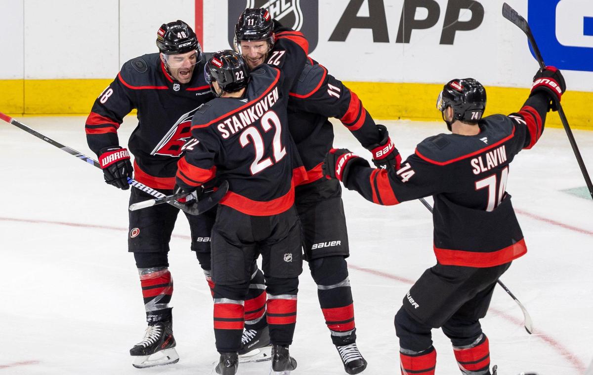 Carolina Hurricanes center Logan Stankoven (22) celebrates with teammate Jordan Staal (11) and Jordan Martinook (48) after scoring his first of two goals in the second period against the New Jersey Devils in the first game of the playoffs on Sunday, April 20, 2025 at Lenovo Center in Raleigh, N.C.