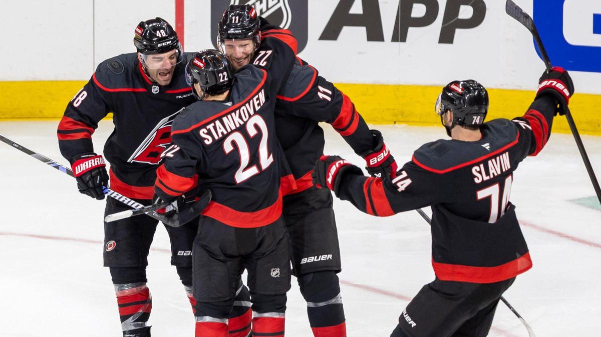 Carolina Hurricanes center Logan Stankoven (22) celebrates with teammate Jordan Staal (11) and Jordan Martinook (48) after scoring his first of two goals in the second period against the New Jersey Devils in the first game of the playoffs on Sunday, April 20, 2025 at Lenovo Center in Raleigh, N.C.