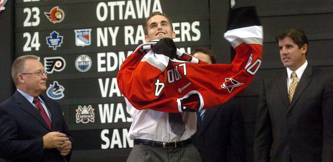 Andrew Ladd puts on the ceremonial jersey after being drafted No. 4 in the first round of the 2004 NHL Draft by the Carolina Hurricanes held at the RBC Center, now known as the Lenovo Center. At left is Canes GM Jim Rutherford; at right is head coach Peter Laviolette.