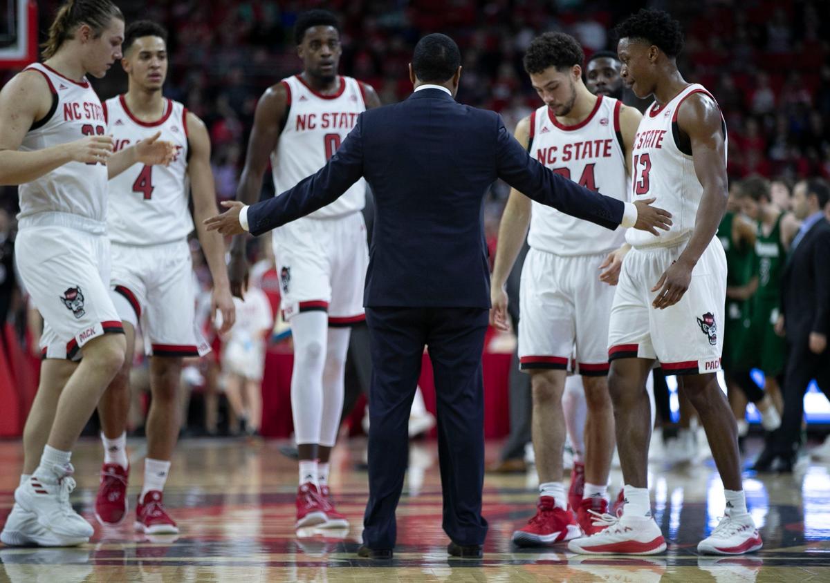 N.C. State head coach Kevin Keatts huddles with his players during a time out in the second half against Loyola on Friday, December 28, 2018 at the PNC Arena in Raleigh, N.C.