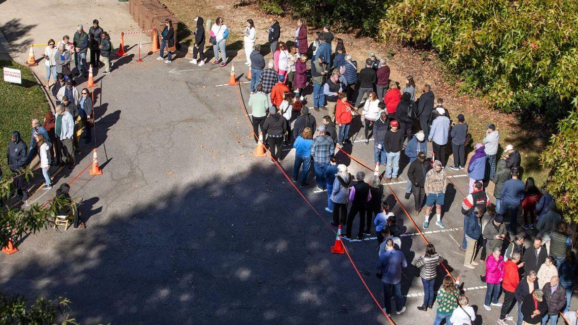 A line curves around the parking lot of the Herb C. Young Recreation Center in Cary, N.C., Thursday morning, Oct. 17, 2024, as people wait to cast their ballots on the first day of early voting in North Carolina.