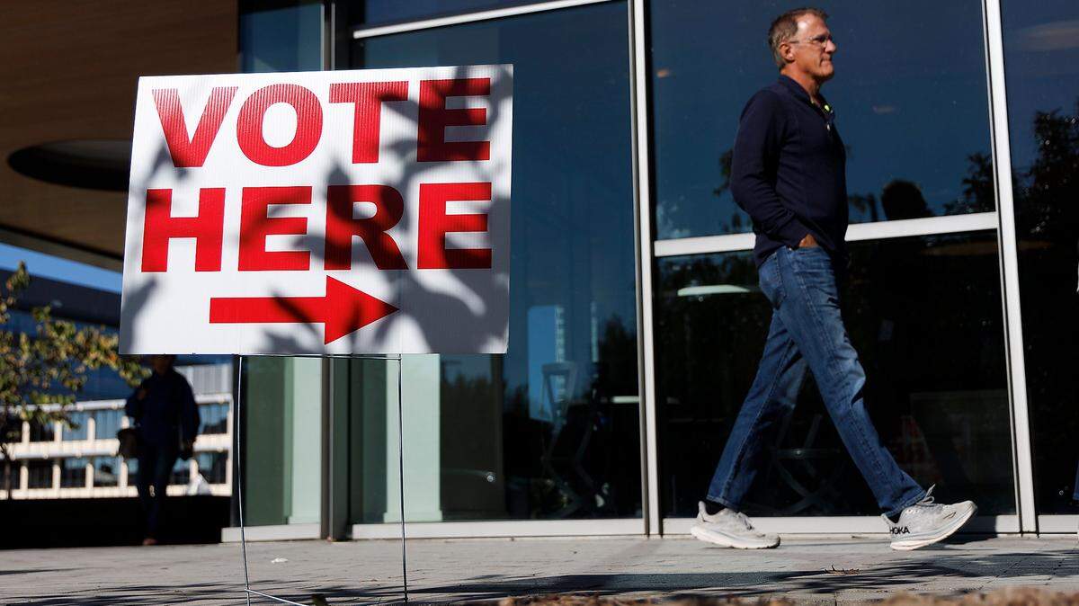 A person walks by a voting sign outside the Durham County Main Library on the first day of early voting, Thursday, Oct. 17, 2024, in Durham, N.C.