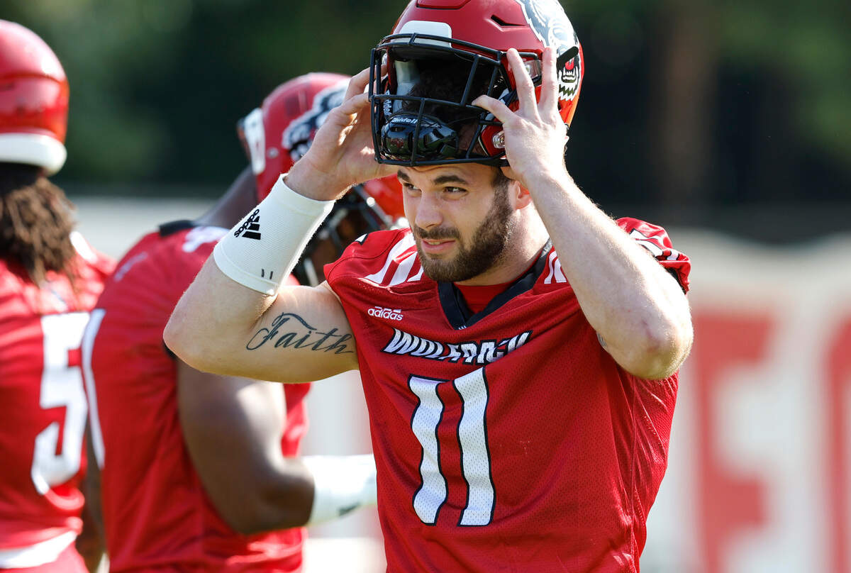 N.C. State linebacker Payton Wilson (11) puts on his helmet at the start of the Wolfpack’s first practice of fall camp in Raleigh, N.C., Wednesday, August 3, 2022.