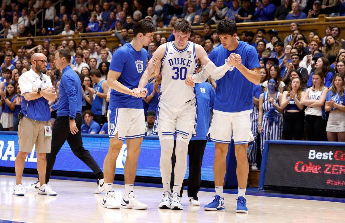 Duke’s Neal Begovich, left, and Stanley Borden help Kyle Filipowski (30) off the court after he was injured during the first half of Duke’s game against Bucknell at Cameron Indoor Stadium in Durham, N.C., Friday, Nov. 17, 2023.