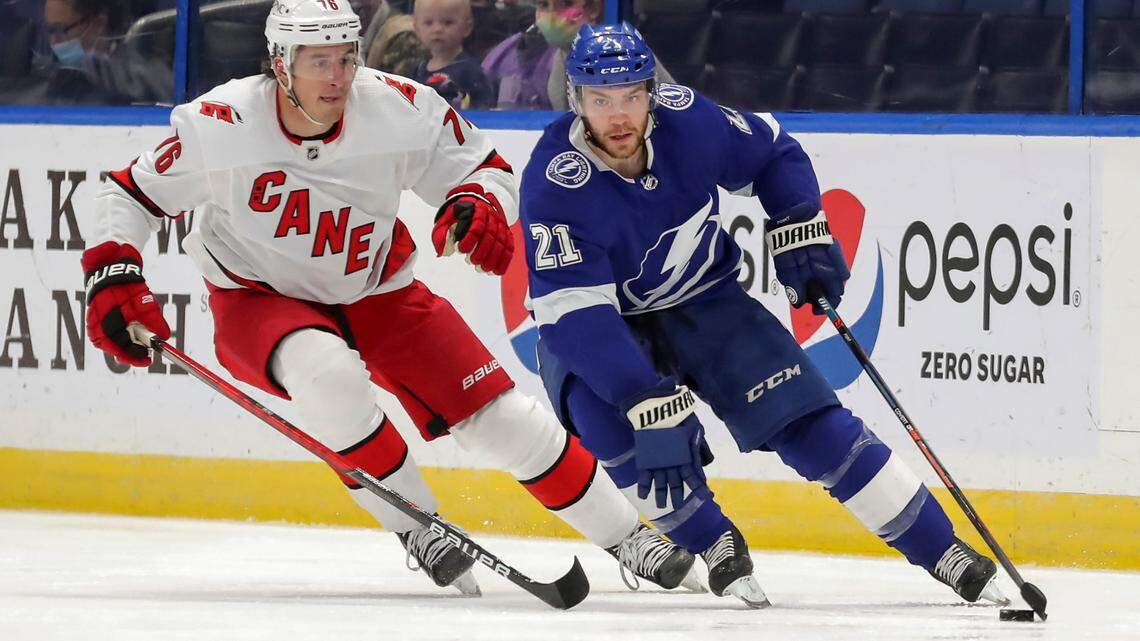 Tampa Bay Lightning’s Brayden Point (21) avoids the check from Carolina Hurricanes’ Brady Skjei during the first period of an NHL hockey game Monday, April 19, 2021, in Tampa, Fla. (AP Photo/Mike Carlso)