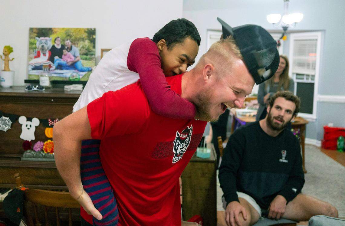 Grayson Ketchie playfully pulls the hat from N.C. State kicker Brayden Narveson as Narveson and other Wolfpack players visit Grayson’s home in Garner Wednesday, Oct. 18, 2023. Ketchie, 12, has been suffering from severe neurological issues since he was a baby. He has been a Wolfpack fan since he was three and the players made a surprise visit to his home that evening.